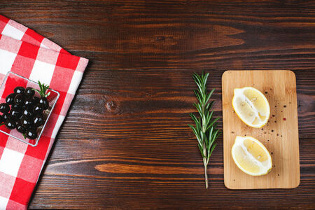 glass bowl of olives  with rosemary and lemon on the wooden table with italian checkered tableclothの写真素材