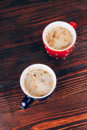 Two cups of coffee with foam standing on wooden tableの写真素材
