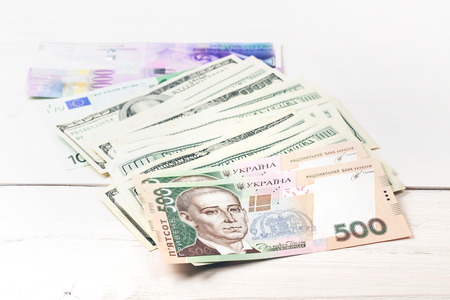 Money: dollars, the hryvnia , the euro , and Swiss francs lying on white wooden table in a rowの写真素材