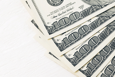 Fan of one hundred dollars banknotes lying on white wooden table, close up viewの写真素材