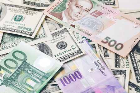 Money: dollars, the hryvnia , the euro , and Swiss francs lying on white wooden table in a rowの写真素材