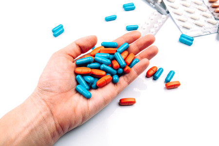 Colored pills in the hand, blue and orange, capsuleの写真素材