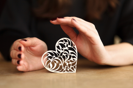 beautiful woman hands holding wooden lace heartの写真素材
