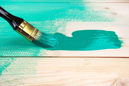 Varnishing a wooden shelf using paintbrush, turquoise colorの写真素材