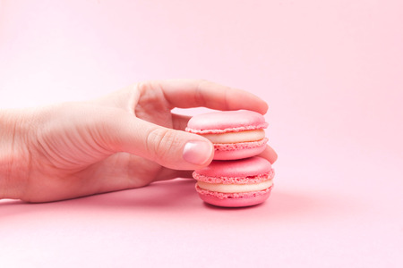 Hands holding pink macaroons on pink backgroundの写真素材