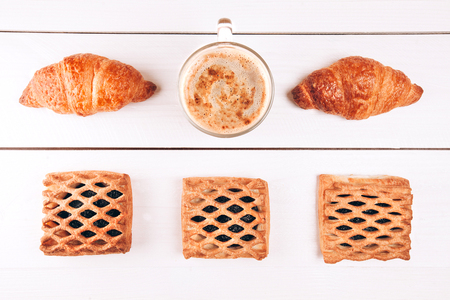 Coffee with croissants and baking lying on white wooden tableの写真素材