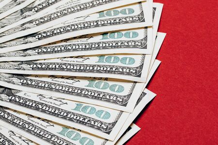 Money in dollars closeup, one hundred dollars banknotes, lying on red backgroundの写真素材