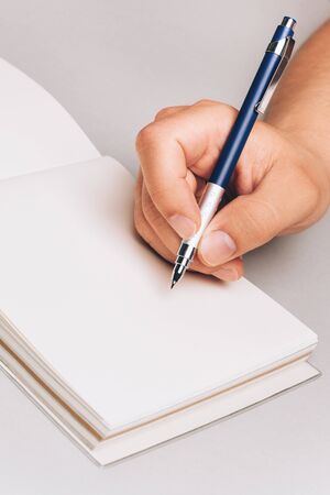 Man, holding pen in his hand and writing something in his note book. Place for text, closeup.の写真素材