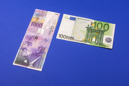comparison of Swiss francs and euros with place for text lying on blue background