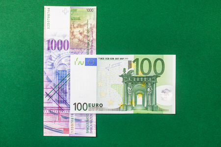 comparison of Swiss francs and euros on green backgroundの写真素材