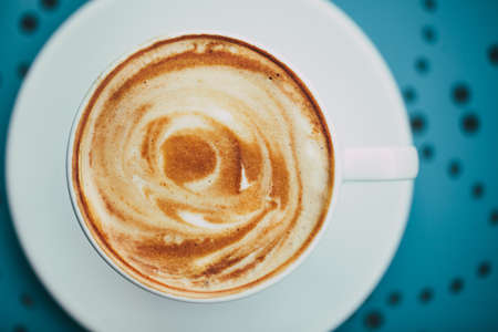 White cup of coffee with crema on a round blue table with a  patternの写真素材