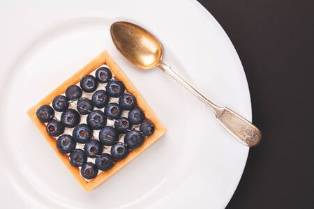 Tartlet with blueberries on a white plate with vintage spoonの写真素材