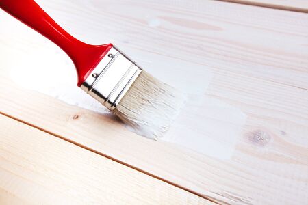Varnishing and painting a wooden shelf using paintbrushの写真素材