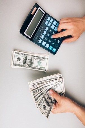 savings, finances, economy and concept - close up of man with calculator counting moneyの写真素材