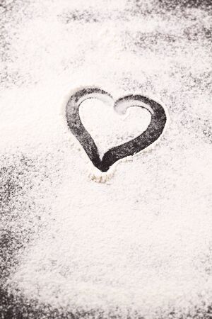 Heart drawn in scattered flour on  black の写真素材