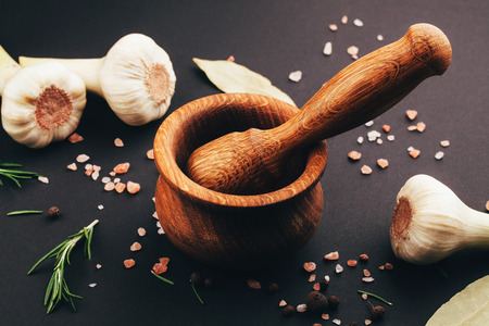 Fresh herbs and spices in wooden mortar on black の写真素材
