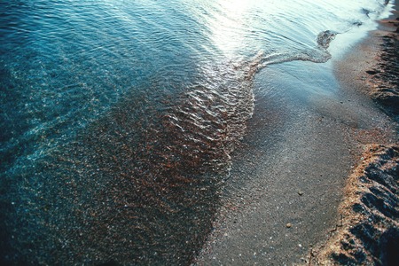 Sea wave on a sandy beach in the eveningの写真素材