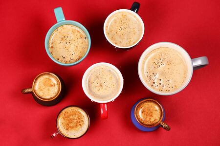 Many different cups of coffee and cappuccino on red background, top viewの写真素材