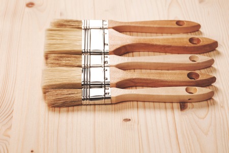 Paint brushes lying on wooden clean textured background, top viewの写真素材