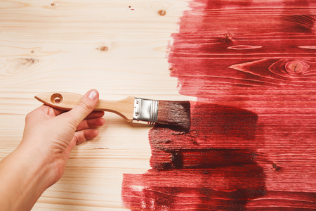 Hand painting red color on wooden table use for home decorated. House renovation. Half - painted surfaceの写真素材