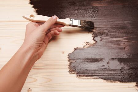 Half painted wooden surface. Hand varnishing or painting natural wood with paint brush and deep brown color.の写真素材