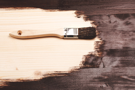 Half painted wooden surface. Deep brown color. Varnishing natural wood with paint brush.の写真素材
