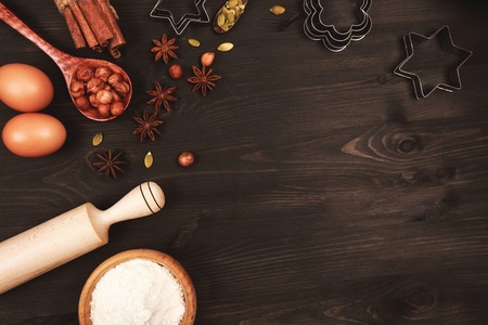 Food ingredients and kitchen utensils for cooking gingerbread or cookies on dark wooden background....