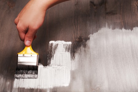 Hand painting white color on wooden table use for home decorated. House renovation. Half - painted surface. Smear of paint brushの写真素材