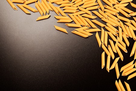 Penne italian pasta forming textured frame on black background.の写真素材