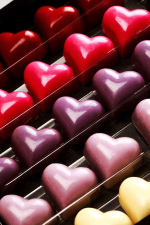 Black opened box with chocolate multicolored hearts, close up. St. Valentine's Day Concept.
