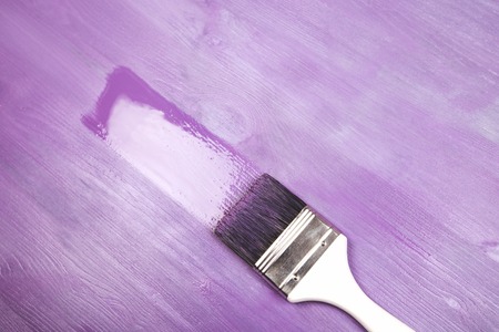 Painting white wooden surface with white paintbrush and violette of lavender color.の写真素材