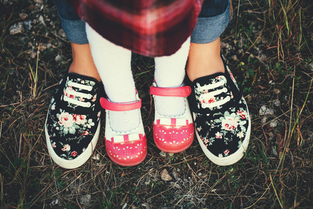 Mother doing first steps with her little daughter. Learning to walk. Mother and daughter feets in boots in the nature.の写真素材