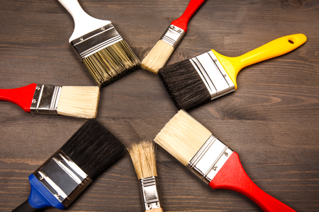 Multicolored clean paint brushes lying on wooden grey textured background, lying in a circleの写真素材