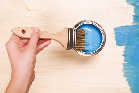 Hand painting blue color on wooden table use for home decorated. House renovation. Half - painted surface. Smear of paint brushの写真素材