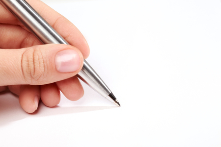 Silver metal pen in hand isolated on white background. Writing process.の写真素材