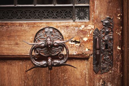 Beautiful old metal door handle with face on an antique wooden door.の写真素材