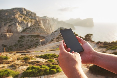 Men's hands holding and using smart phone in the mountains, Mallorca, Spain. Concept of excellent...