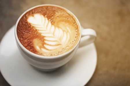 Cup of cappuccino with perfect latte art on the table. Top view, macro.の写真素材