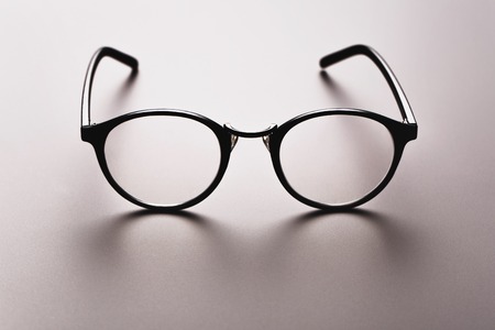 Black satine plastic circle eye glasses for womenor hipster, lying on grey background with accurate shadow.の写真素材