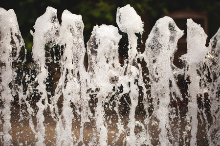 Powerful water jets of city fountain with bubbles and foam.の写真素材