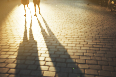 Blurred people background in magic sunset light with lond shadows.の写真素材