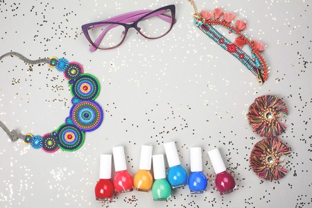 Beautiful multicolored frame made of woman accessories and rainbow of nail polishes. All stuff is lying on grey festive background. Place for your text.の写真素材