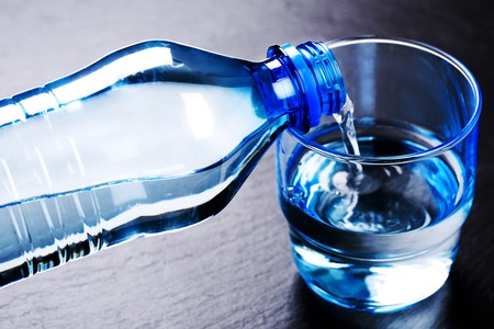 Water flowing from a plastic bottle into a glassの写真素材