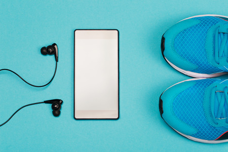 Black headphones, smart phone and blue sneakers on blue background. Concept of active lifestyle.の写真素材