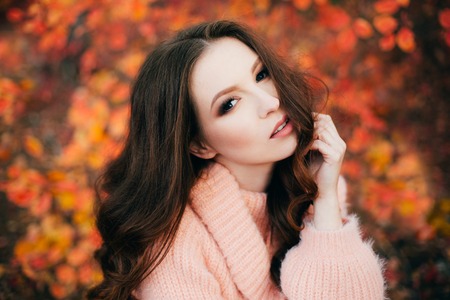 Young sexy thoughtful woman with long hair in fluffy sweater, in orange autumn forest.の写真素材