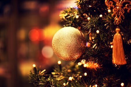 Fir branch with balls and festive lights on the Christmas background with sparkles.