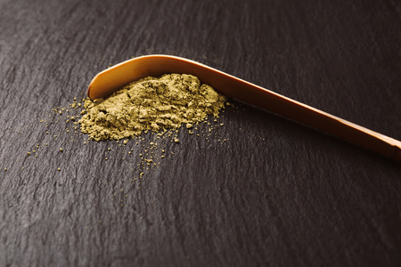 Special bamboo spoon for green powdered matha tea isolated on black stone textured background.の写真素材