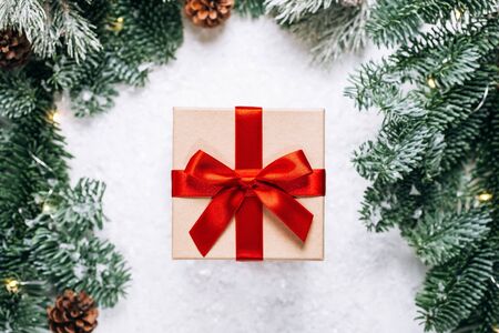 Christmas presents with red ribbon on white wooden background in a frame made of fir branches with canes. Flat lay styleの写真素材