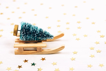 Beautiful christmas card. Little toy pine on wooden sleigh on sparkling background.の写真素材