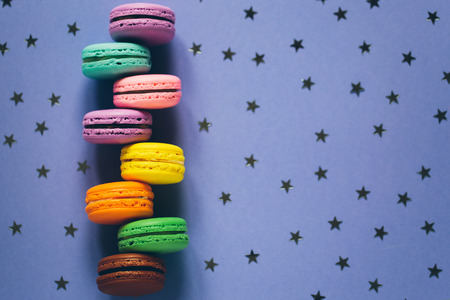 Colorful macaroons on violet background with little stars. Top view, flat lay style.
